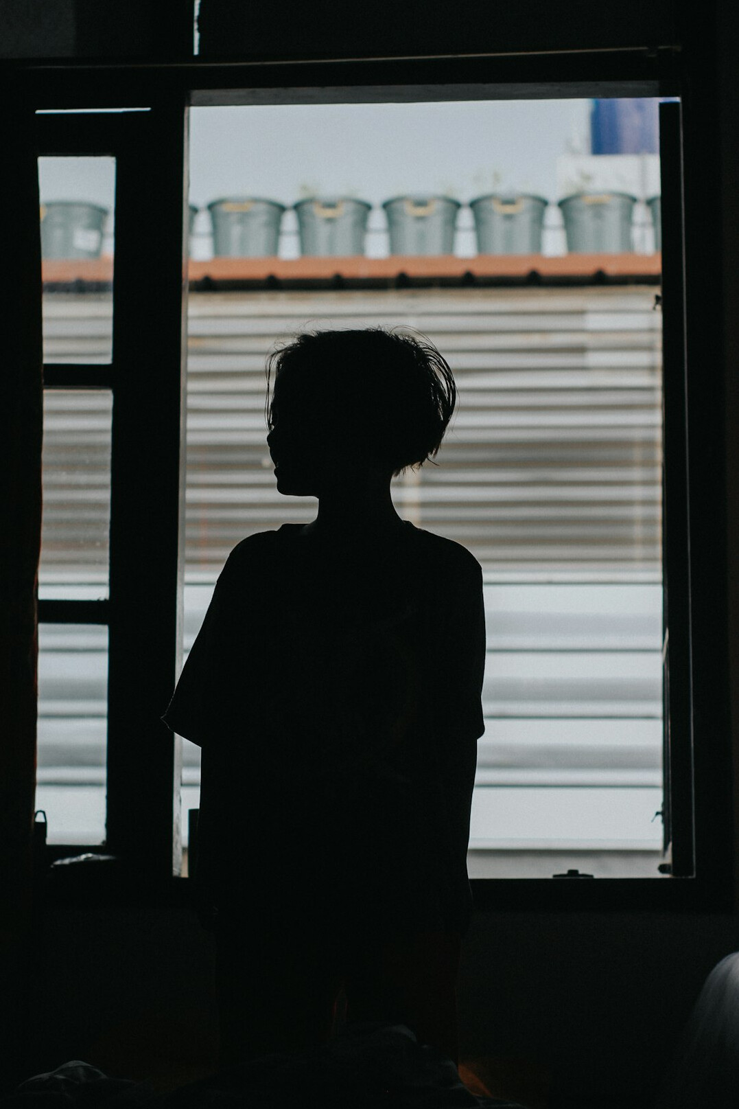Anonyme Silhouette einer Person vor einem großen Fenster, von hinten fotografiert