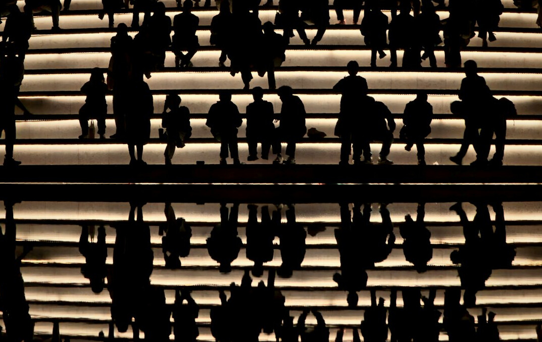 Silhouetten anonymer Menschen, die einen weiten Platz aus der Distanz überqueren